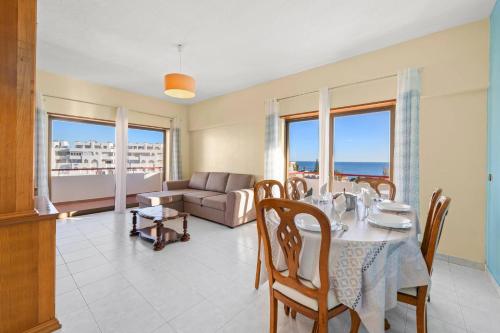a dining room with a table and a couch at Apartamentos Vista Mar in Armação de Pêra