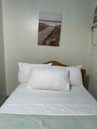 a bed with white pillows and a picture on the wall at Joy's Home Rental in Tagbilaran City