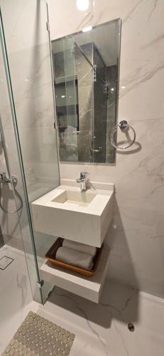 a white bathroom with a sink and a mirror at Modern Omani Inspired Apartment in Muscat in Muscat
