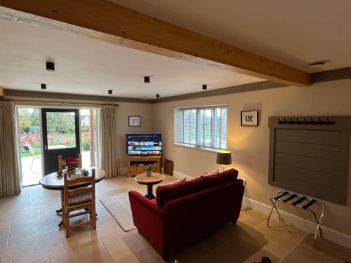 a living room with a red couch and a tv at Award Winning Lodge at Ewen Barn, Ewen, Cirencester in Cirencester