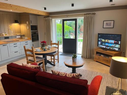 a living room with a couch and a table with a tv at Award Winning Lodge at Ewen Barn, Ewen, Cirencester in Cirencester
