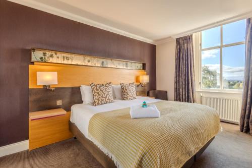 a bedroom with a large bed with a large window at Apex Dunblane Hydro in Dunblane