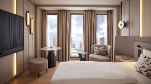 a hotel room with a bed and a chair and window at ATLANTIC Hotel Frankfurt in Frankfurt