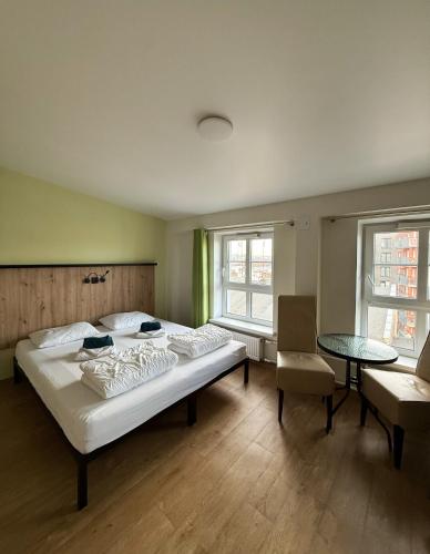a bedroom with a bed and a table and two windows at FOKA Hostel in Wrocław