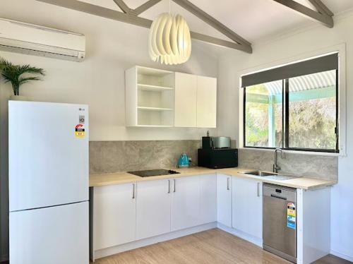 a kitchen with white cabinets and a white refrigerator at Beachside Cabin No 1 at Island Beach in Island Beach