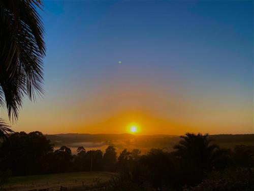 a sunset over a field with the sun in the sky at The Bloom Farm Cottage 