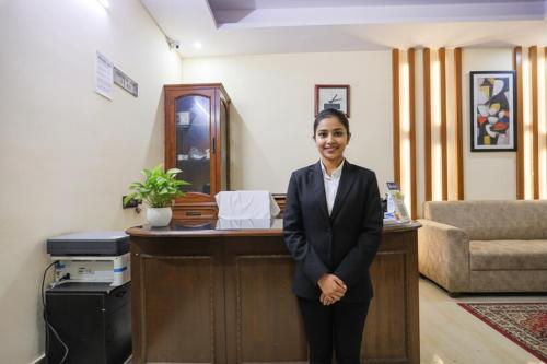 ノイダにあるFabHotel HM Palaceの机前に立つ女