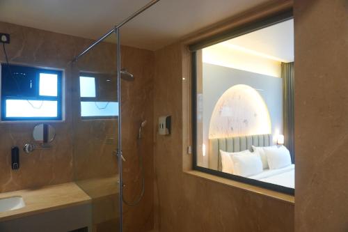 a bathroom with a glass shower with a bed and a mirror at The Lovedale Kodaikanal Stay & Hotel in Kodaikānāl