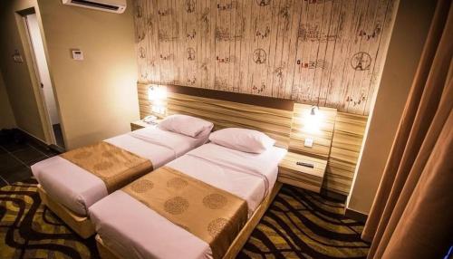 a hotel room with two beds and a wooden wall at Victory City Hotel Crystal Bay in Iskandar Puteri