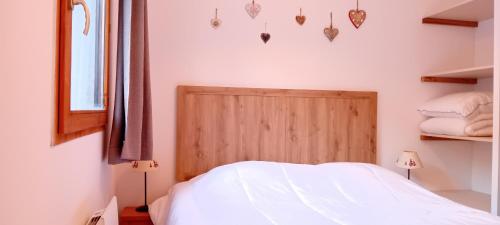 a bedroom with a white bed and a wooden headboard at Balcons G 013 - PARC NAT VANOISE appart 8 pers in Termignon