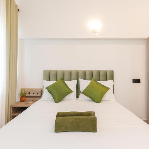 a white bed with a green pillow on it at Skyport Villa Katunayaka in Katunayaka