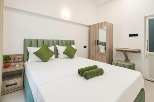 Skyport Villa Katunayaka في كاتوناياكى: غرفة نوم بسرير أبيض كبير مع وسائد خضراء