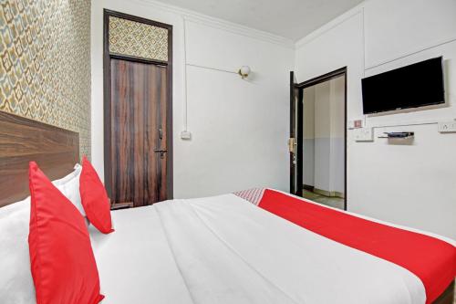 a bedroom with a bed with red pillows and a television at Goswami property in Jaipur