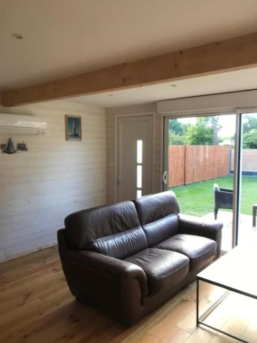 - un canapé en cuir dans le salon avec une porte coulissante en verre dans l'établissement Petite Maison T2, à La Celle-sous-Gouzon