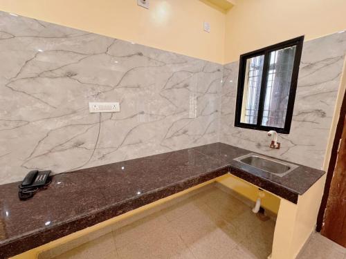 ein Badezimmer mit einer Theke, einem Waschbecken und einem Fenster in der Unterkunft Studio 401 Cityscape Retreat in Deoghar