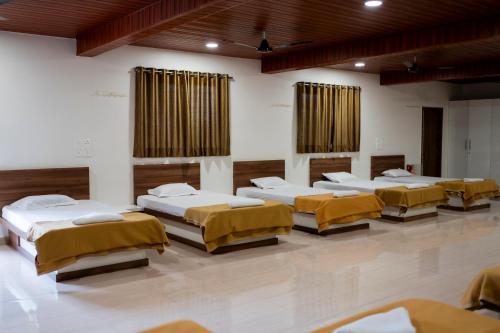 a row of beds in a room at Ambika Hills Resort in Junnar