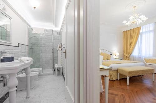 Un baño con lavabo y una cama en una habitación. en Hotel Croce Bianca, en Asiago