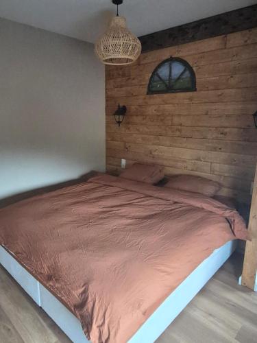 Un dormitorio con una cama con una pared de madera. en B&B Lindehoeve Texel, en Den Hoorn