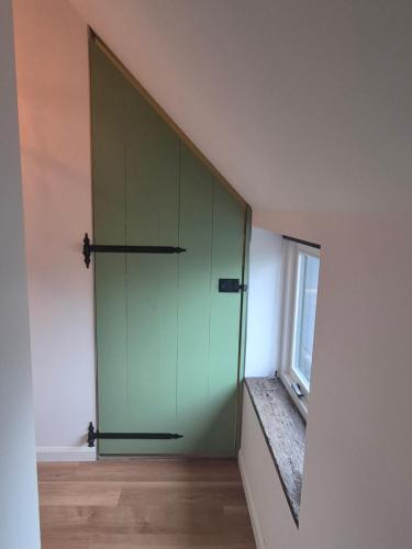 Una puerta verde en una habitación con ventana en B&B Lindehoeve Texel, en Den Hoorn