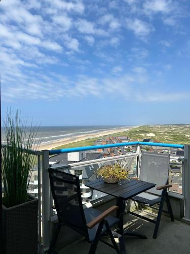 a table and chairs on a balcony with the beach at Sterflat 205 in Egmond aan Zee