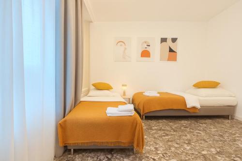 two beds in a room with orange sheets at Representative City Villa in Meerbusch