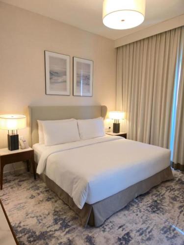 a bedroom with a large white bed with two lamps at 3 Bedroom Suite Building-Wide Balcony Fujairah in Fujairah