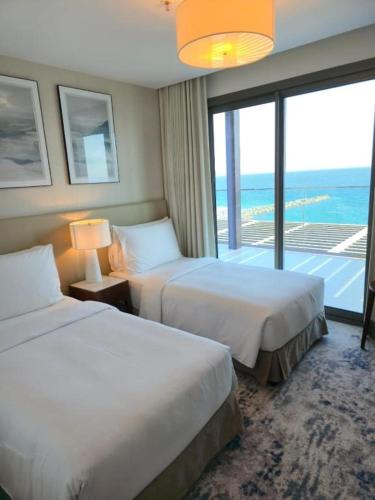 a hotel room with two beds and a large window at 3 Bedroom Suite Building-Wide Balcony Fujairah in Fujairah