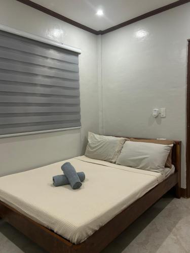 a bed with a blue teddy bear sitting on it at Sinta Stay in El Nido