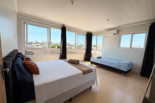 a bedroom with a bed and a large window at Sobrado de 3 quartos in Capão da Canoa