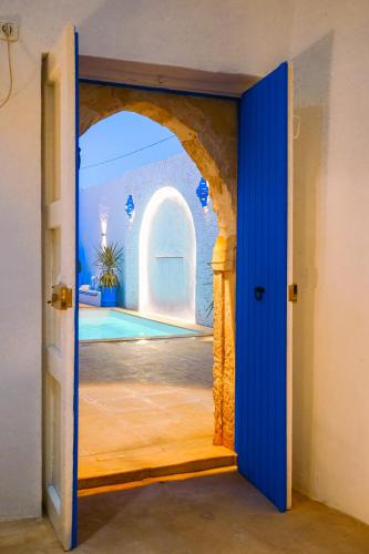 a blue door with a view of a swimming pool at Dar Ayline in Erriadh