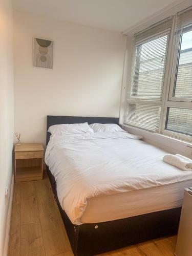 a bedroom with a large white bed with a window at Zone 2 En-Suite Rooms Peckham Maisonette in London