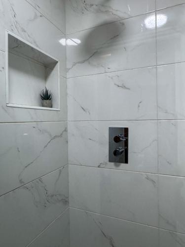a white marble shower with a mirror and a plant at Zone 2 En-Suite Rooms Peckham Maisonette in London