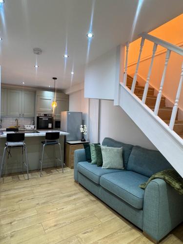 a living room with a blue couch and a staircase at Zone 2 En-Suite Rooms Peckham Maisonette in London