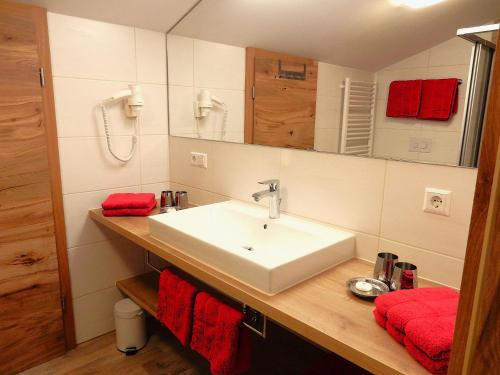 a bathroom with a white sink and red towels at Gästehaus Schönfeld in Reit im Winkl