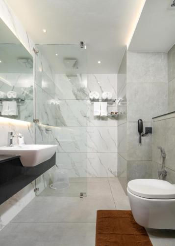 a white bathroom with a sink and a toilet at Crystal Suites in Badagara