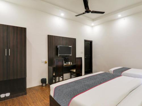 a bedroom with a bed and a desk with a television at Super Hotel O Centrum in Gorakhpur