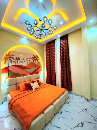 a bedroom with a large bed with an orange blanket at Eden- Jacuzzi Privé et Terasse à 5mn de la plage in Dakar