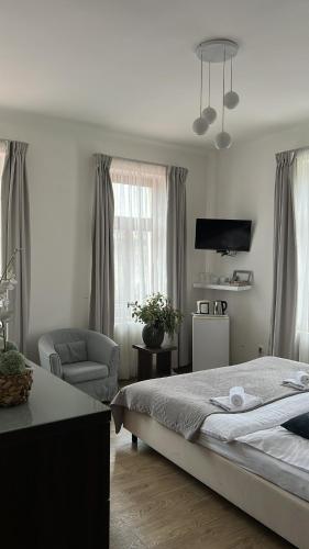 a bedroom with a large bed and a chair at Penzion Marjána in Mníšek pod Brdy