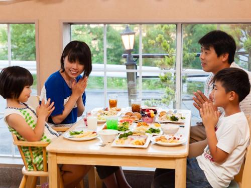 una familia sentada alrededor de una mesa comiendo comida en Shirakabako Hotel Paipuno Kemuri en Chino