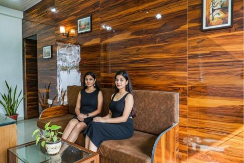 Twee vrouwen zitten op een bank in een kamer met houten muren. bij FabHotel Bliss Executive - shaniwar wada in Pune