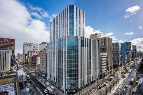 a tall glass building in the middle of a city at The Gate Hotel Sapporo by Hulic in Sapporo