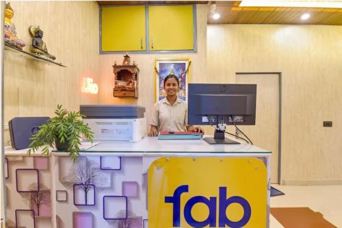 FabHotel Doon Classic Homestay في دهرادون: رجل يقف عند مكتب وبه جهاز كمبيوتر