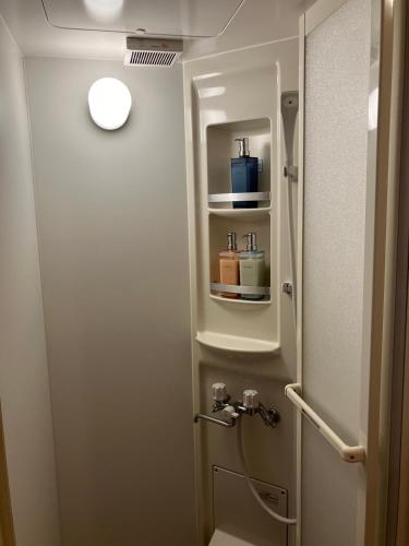 a bathroom with a toilet and a door with a shelf at 一棟貸宿ほしなや in Nagano