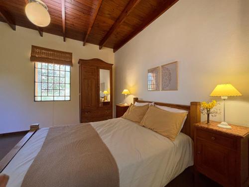 Un dormitorio con una cama grande con sábanas blancas y una ventana. en Cabañas Estancia Balumba, en Capilla del Monte