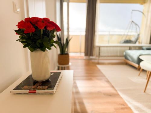 een vaas gevuld met rode bloemen zittend op een tafel bij Neu! Hirschgrund 10 OG Panorama, Sauna, Pool in Braunlage