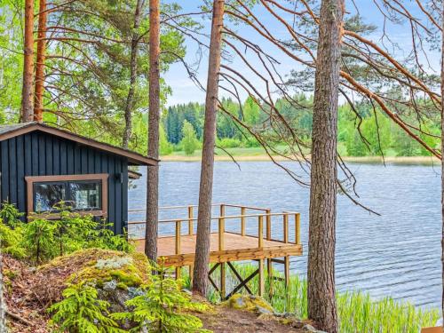 a cabin on the shore of a lake with a dock at Holiday Home Louhikko by Interhome in Houhajärvi