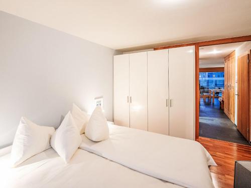Un dormitorio con una cama blanca con almohadas blancas. en Apartment Chesa Promulins by Interhome, en Samedan