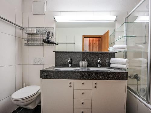 Un baño con dos lavabos y un inodoro. en Apartment Chesa Promulins by Interhome, en Samedan