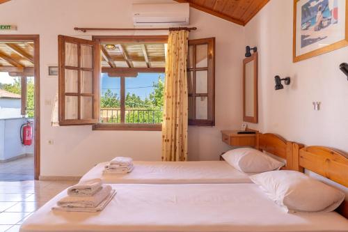 two beds in a room with a window at Amalia Studios Skiathos in Skiathos Town