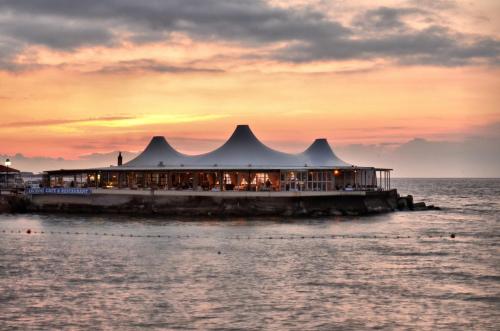 a restaurant on a pier in the water at sunset at DOME Hotel & Casino Central Kyrenia ! in Kérynia
